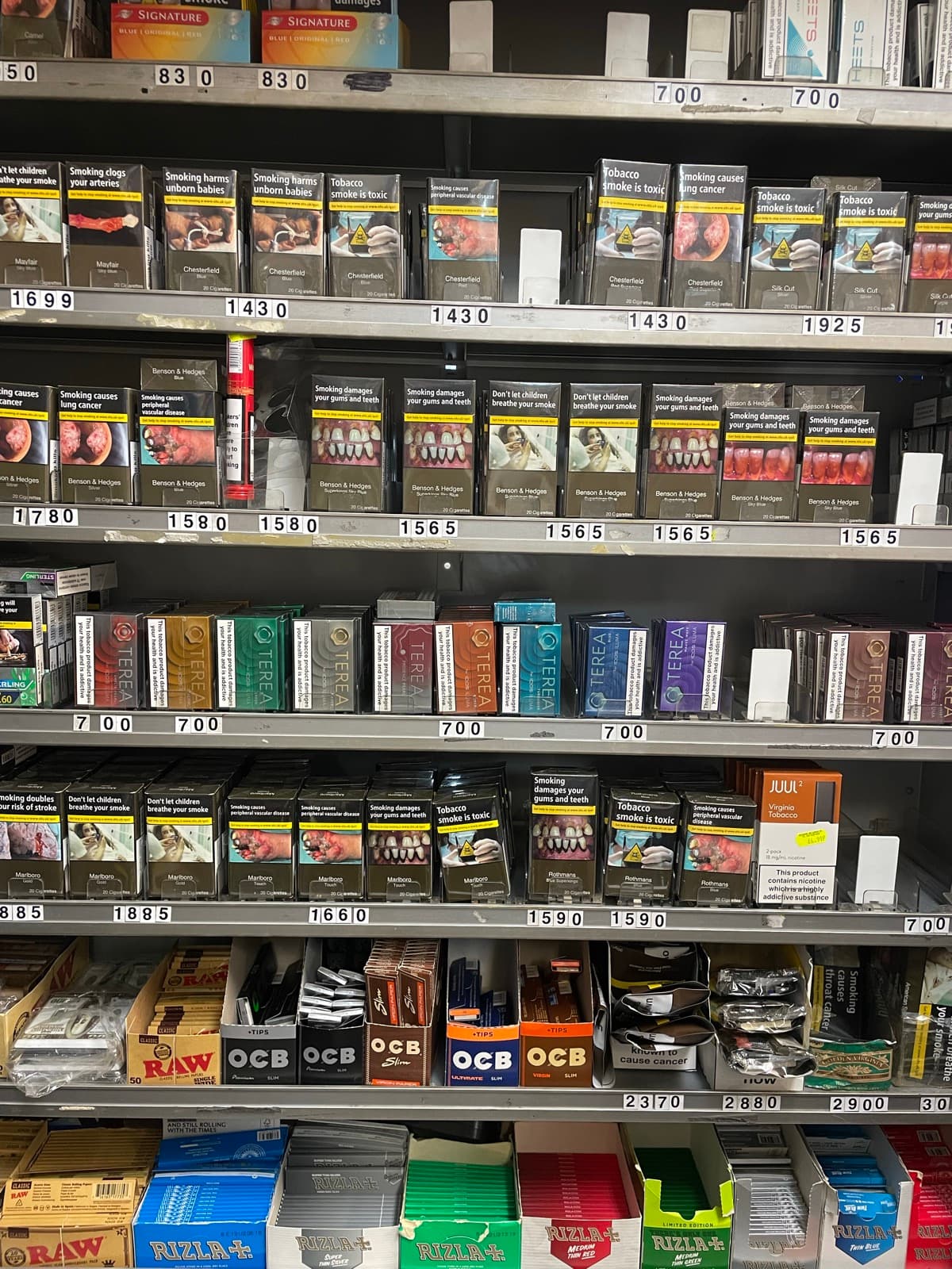 Shelves of cigarettes, rolling papers, disposable vapes, shisha pipes and charcoal behind the counter